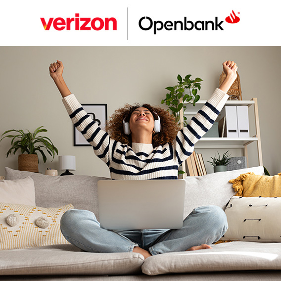 Woman sitting on a couch with a laptop and headset, joyfully raising her hands